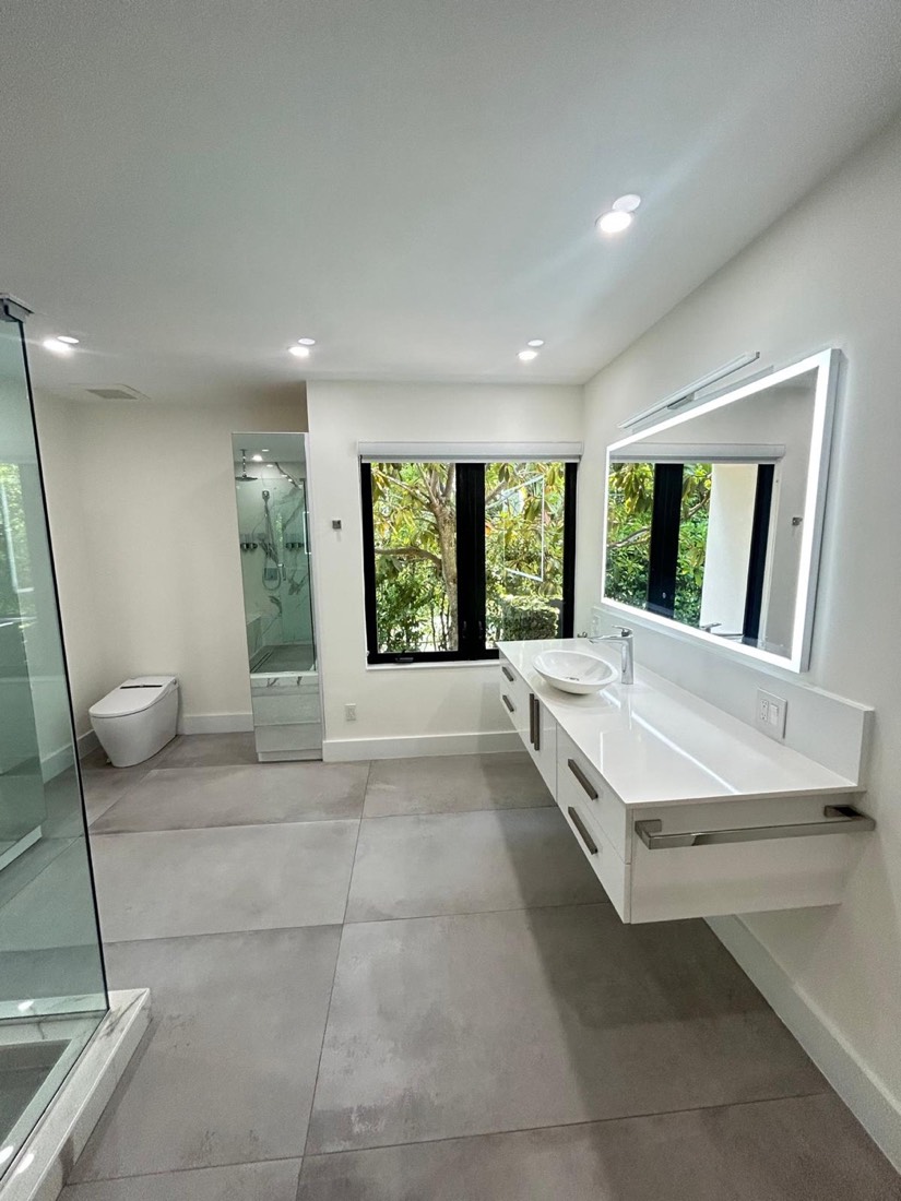 Modern bathroom remodel with fresh paint and backlit mirrors